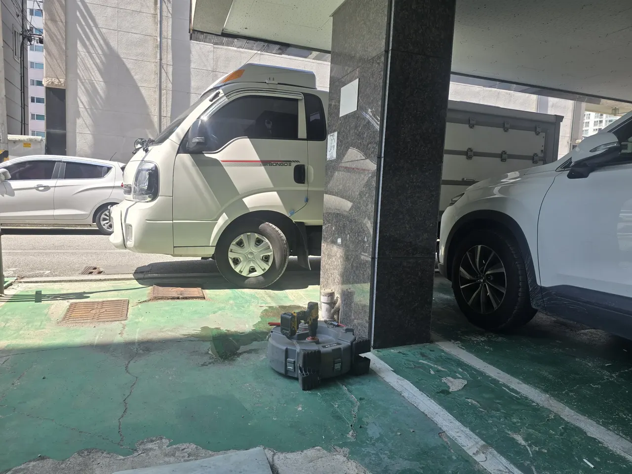 지하주차장 기둥 옆에 놓인 전동스프링릴 장비와 드릴, 벽면 배관 밸브가 보이는 현장