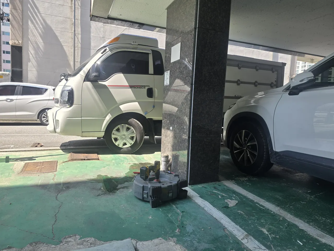 지하주차장 바닥에 놓인 전동스프링릴 장비와 드릴, 작업자 없이 장비만 있는 모습