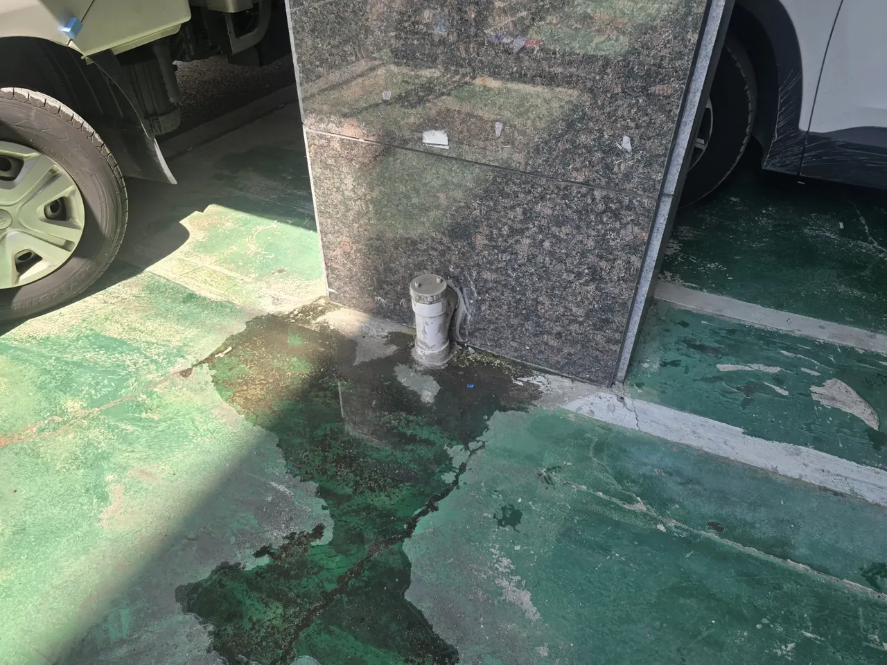 건물 외벽 모서리에 노출된 배수관 청소구 하단 바닥에 누수로 보이는 흔적이 넓게 퍼진 현장, 작업 전 증상