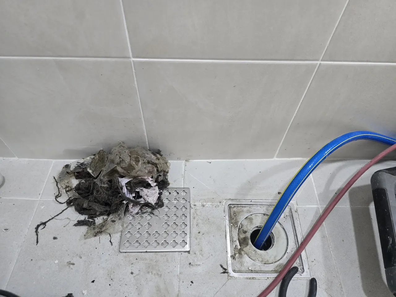 바닥배수구 옆에 제거된 머리카락·휴지 뭉치 이물질, 작업 완료 후 확인 모습